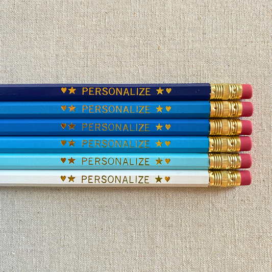 Explore our vibrant BEACHY BLUES personalized pencil set! Elevate your desk with these hand-pressed pencils, customizable with a name or phrase. Made in the USA, each set includes 6 #2 pencils with latex-free erasers and gold foil personalization. Say goodbye to boring pencils today!